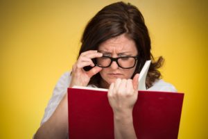 woman with black eye glasses trying to read a book