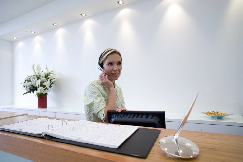 Receptionist behind desk with headset scheduling appointments