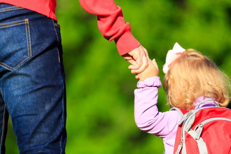 daughter holding her parent's hand while walking