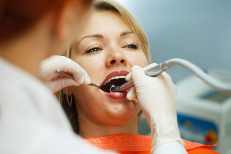 woman having her teeth cleaned by her dentist
