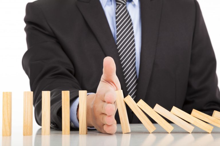 a businessman showing interruption by hindering a domino reaction