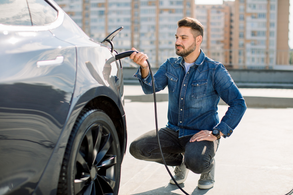 bearded guy charging his electric vehicle while sitting