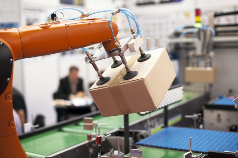 An orange robot arm holding a cardboard box