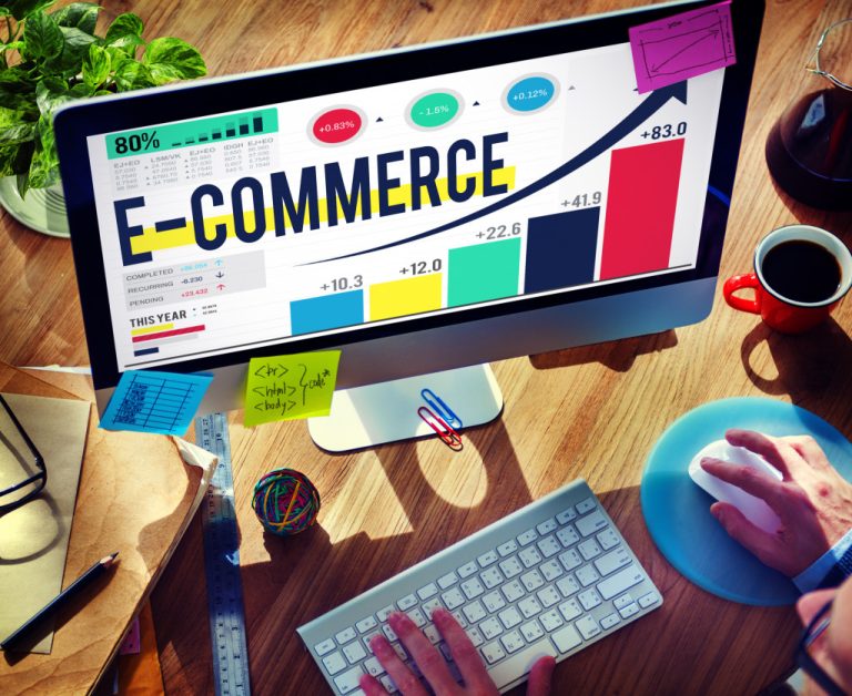 person looking at e-commerce concept and graphs in computer in cluttered desk