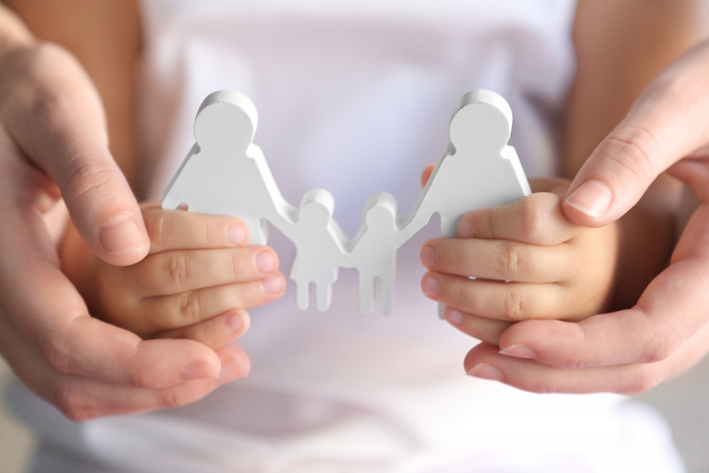 coparenting represented by a young child holding paper doll of mother and father with two kids