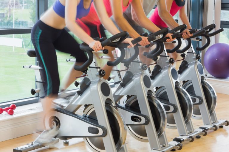 Young people working out on exercise bikes at a gym.