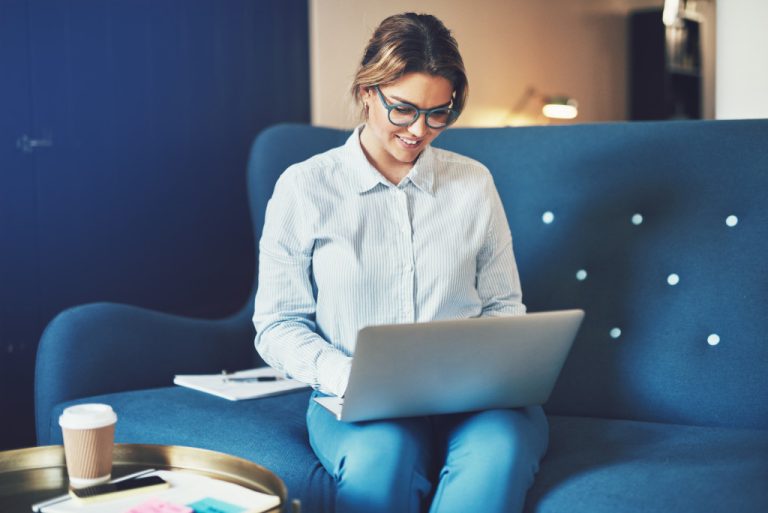laptop while sitting on a sofa at home
