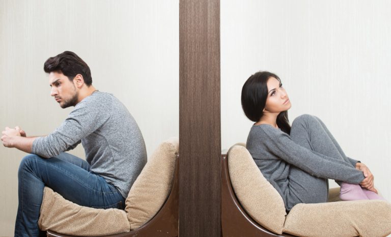 man and woman sitting on either side of a wall