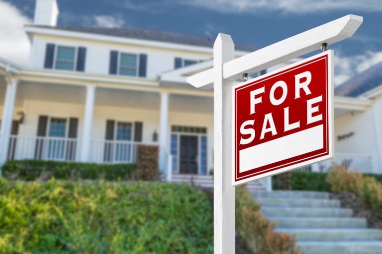 A house with a FOR SALE sign outside
