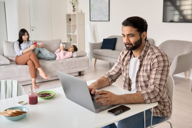 a man working while wife and daughter are at the sofa