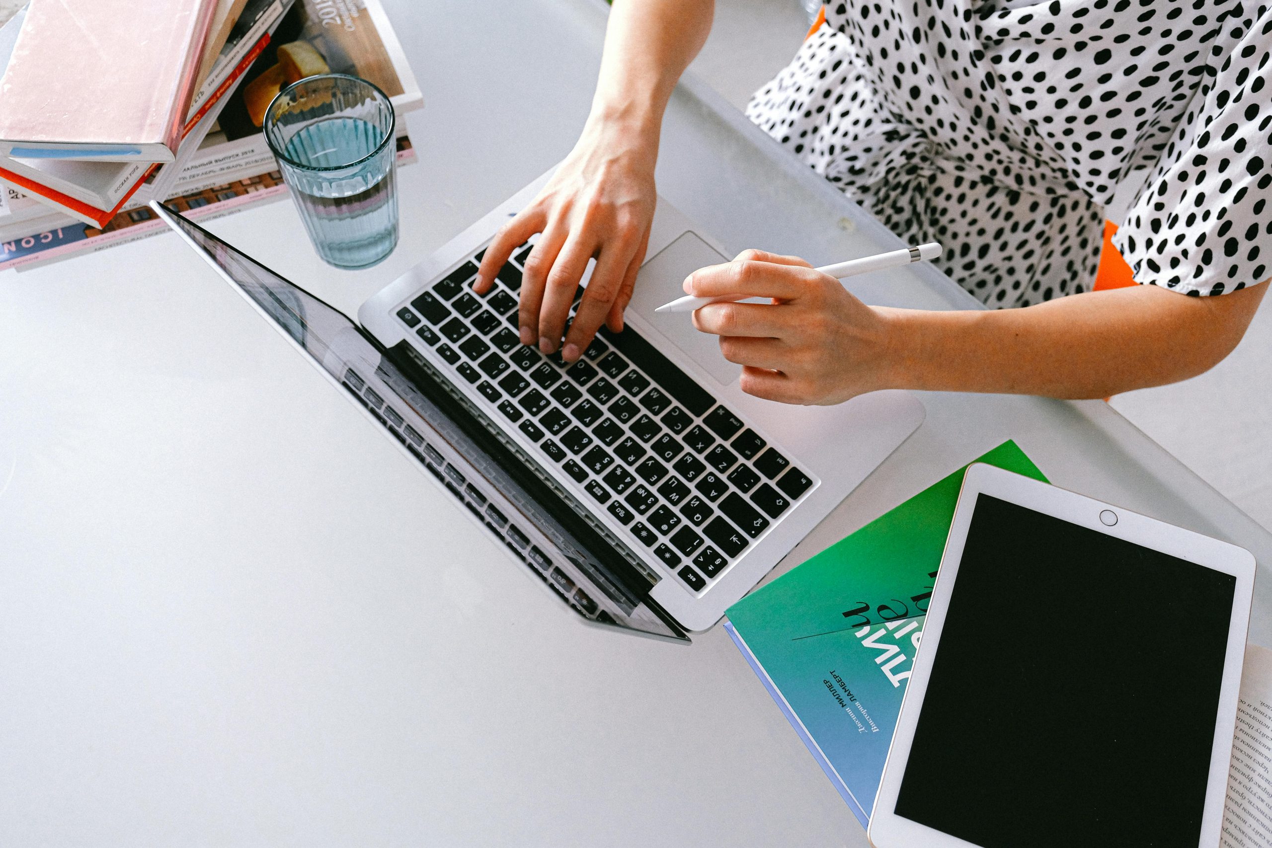 woman working on a laptop with a tablet next to it