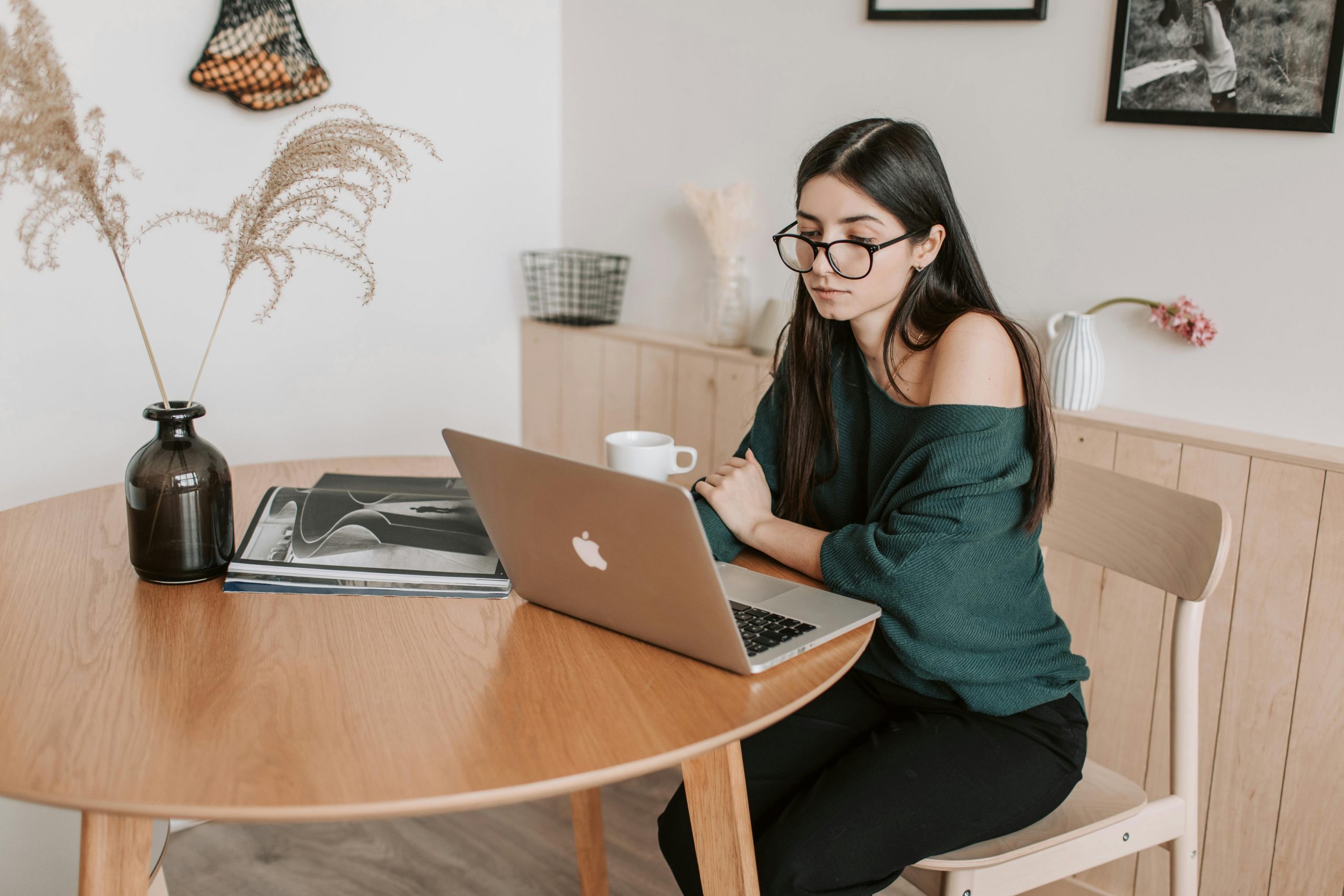 woman wearing eyeglasses, working on her laptop at home